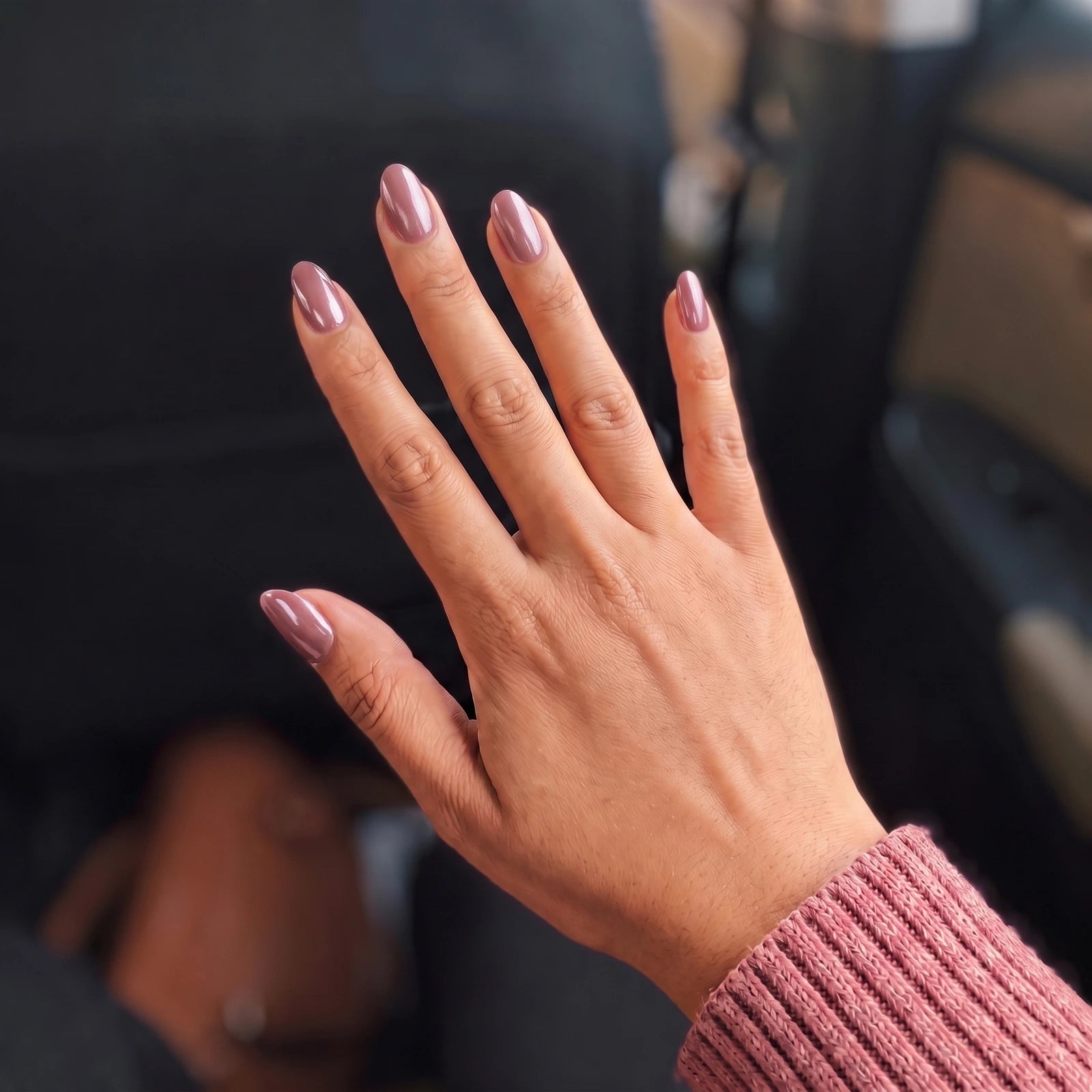 The same hand with a glossy mauve cat-eye manicure